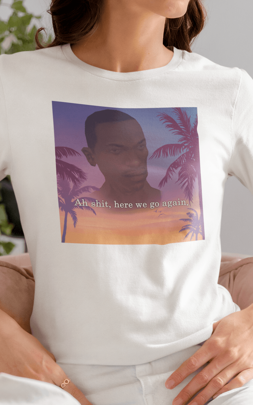 A woman wearing a white T-shirt with an aesthetic miami imagery and cj from GTA San Andreas in the background written &quot;Ah shit, here we go again.&quot;