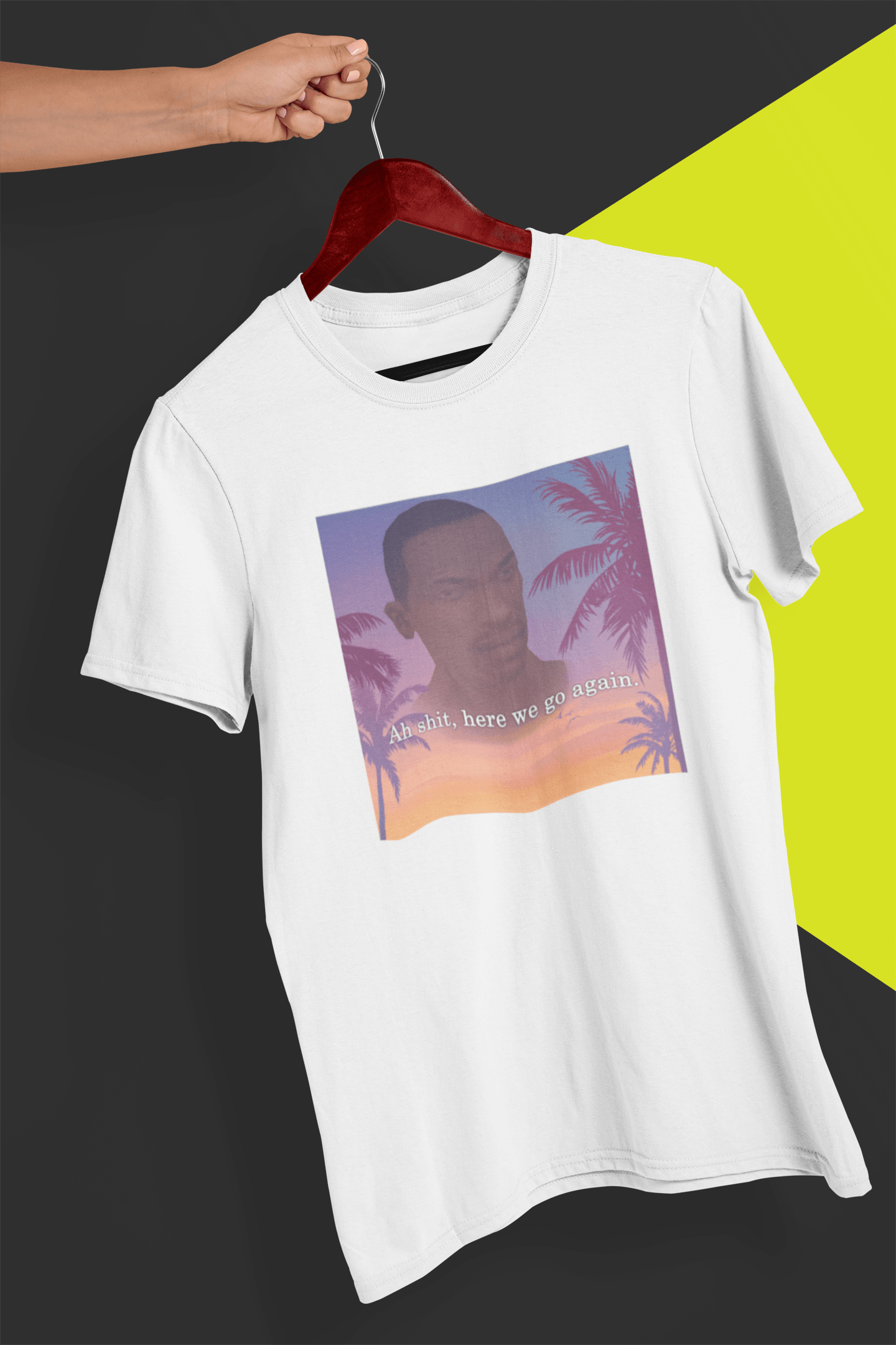 A white T-shirt with an aesthetic miami imagery and cj from GTA San Andreas in the background written &quot;Ah shit, here we go again.&quot;, held by a hand against a split black and yellow background.