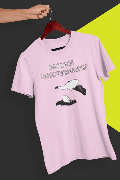 A pink T-shirt with &quot;BECOME UNGOVERNABLE&quot; in black text and a white graphic of a leaping man onto a judge, held on a red hanger against a split black and yellow background.