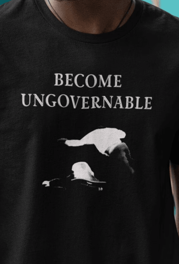 A person in a black T-shirt with &quot;BECOME UNGOVERNABLE&quot; text and a white graphic of a leaping man onto a judge.