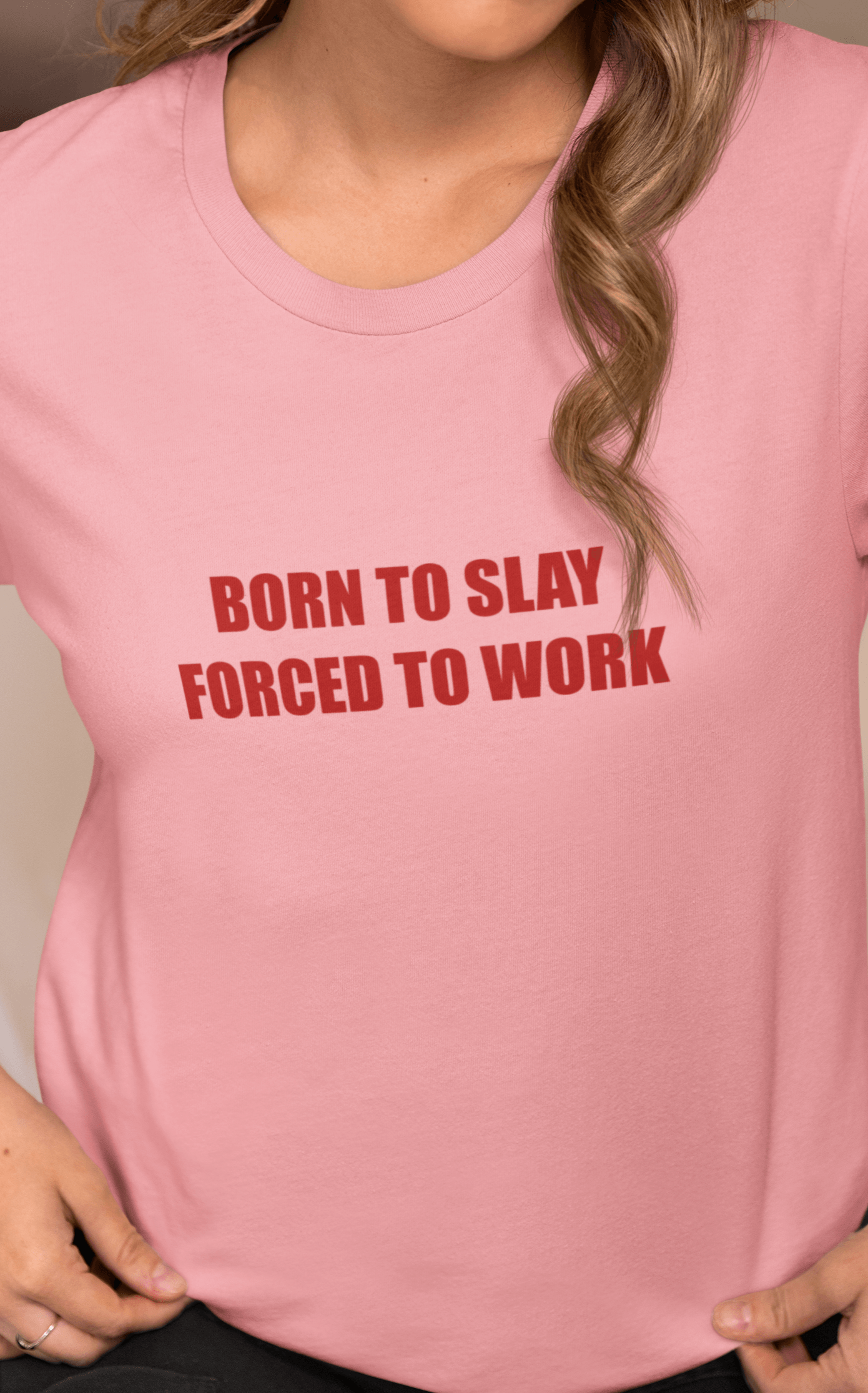 A woman wears a pink T-shirt that says &quot;Born to slay, forced to work&quot;.