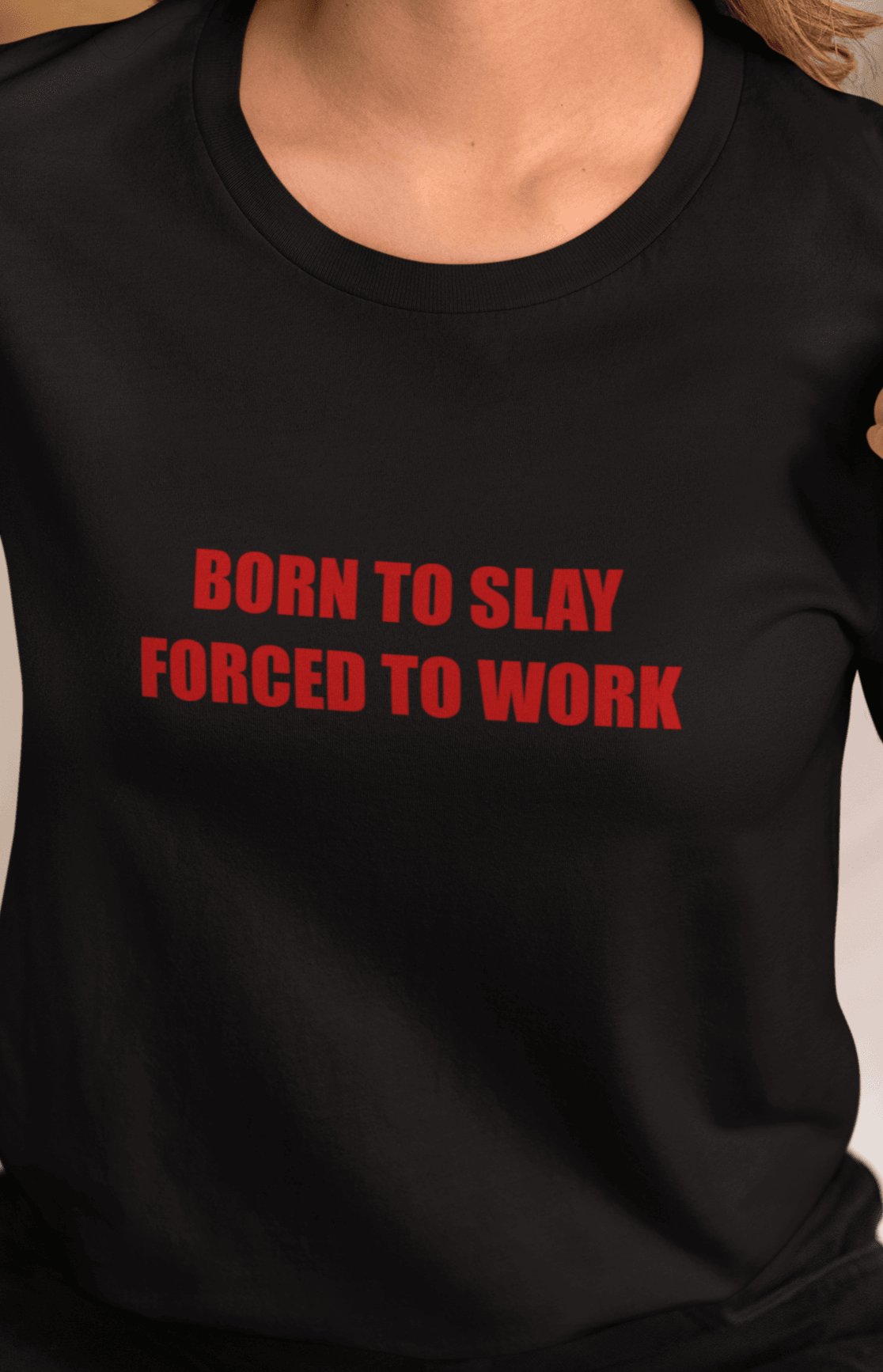 A woman wears a black T-shirt that says &quot;Born to slay, forced to work&quot;.