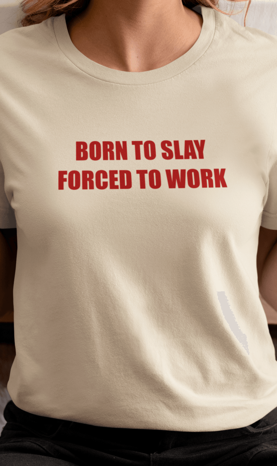 A woman wears an off-white T-shirt that says &quot;Born to slay, forced to work&quot;.