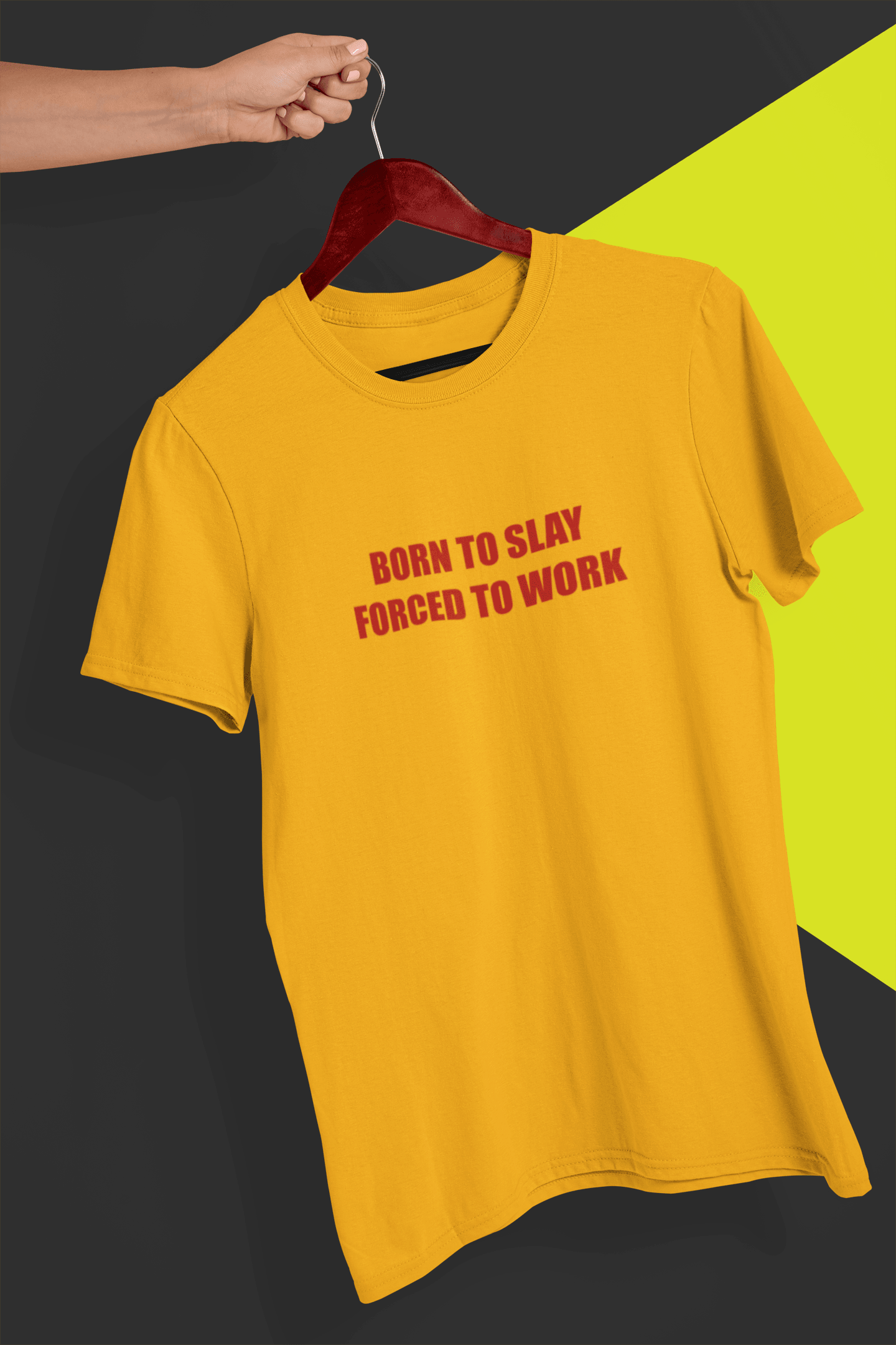 A yolk colored T-shirt that says &quot;Born to slay, forced to work&quot;, held by a hand against a split black and yellow background.