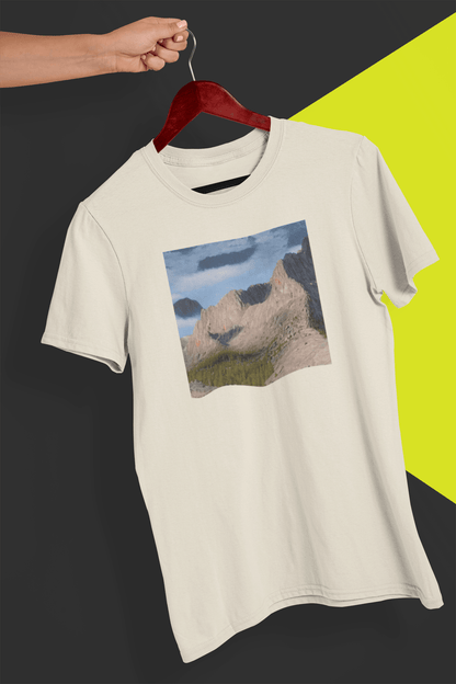 An off-white T-shirt featuring an AI generated landscape that looks like a cat taking a selfie staring at the camera, held by a hand against a split black and yellow background.