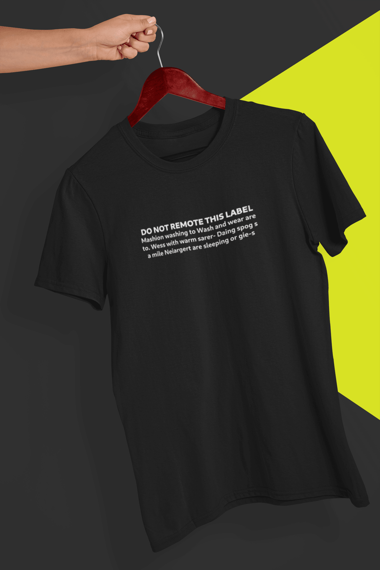 A black T-shirt that says &quot;DO NOT REMOTE THIS LABEL Mashion washing to Wash and wear are to. &quot;, is hung on a red hanger, held by a hand against a split black and yellow background.