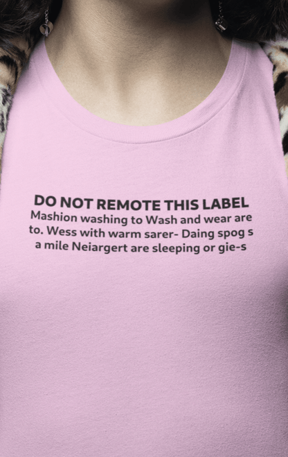 A man wears a pink T-shirt that says &quot;DO NOT REMOTE THIS LABEL Mashion washing to Wash and wear are to. Wess with warm sarer- Daing spog s a mile Neiargert are sleeping or gie-s&quot;.