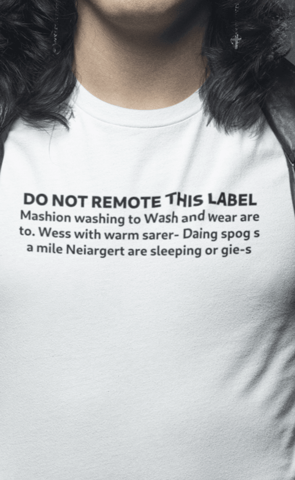 A man wears a white T-shirt that says &quot;DO NOT REMOTE THIS LABEL Mashion washing to Wash and wear are to. Wess with warm sarer- Daing spog s a mile Neiargert are sleeping or gie-s&quot;.