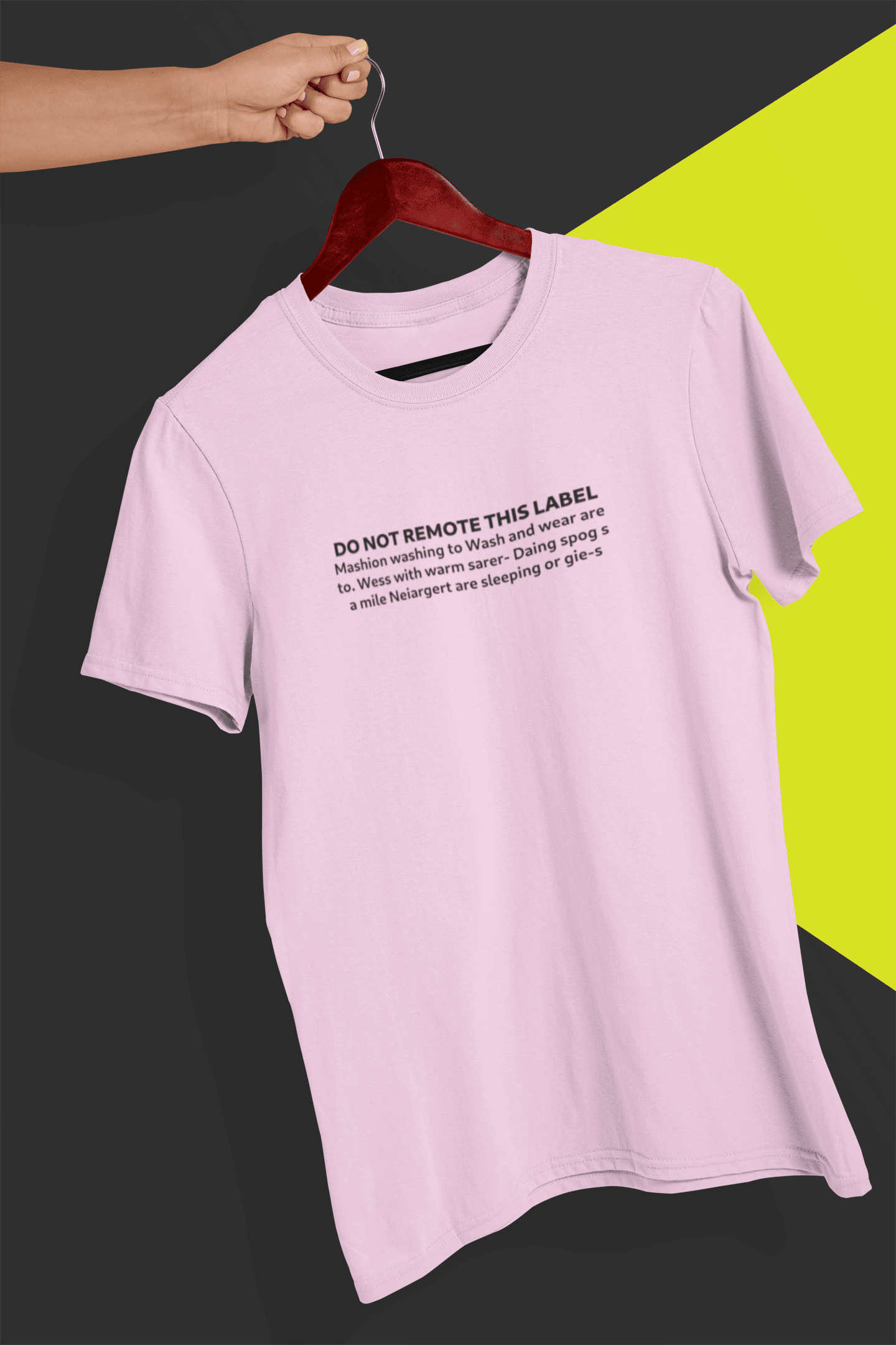 A pink T-shirt that says &quot;DO NOT REMOTE THIS LABEL Mashion washing to Wash and wear are to. &quot;, is hung on a red hanger, held by a hand against a split black and yellow background.