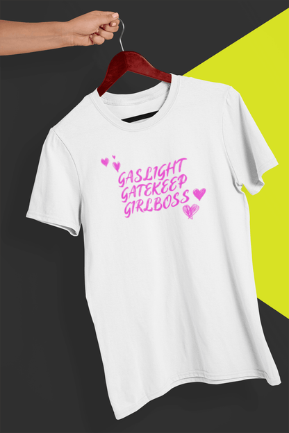 A white T-shirt that says &quot;Gaslight, Gatekeep, Girlboss&quot;, held by a hand against a split black and yellow background.