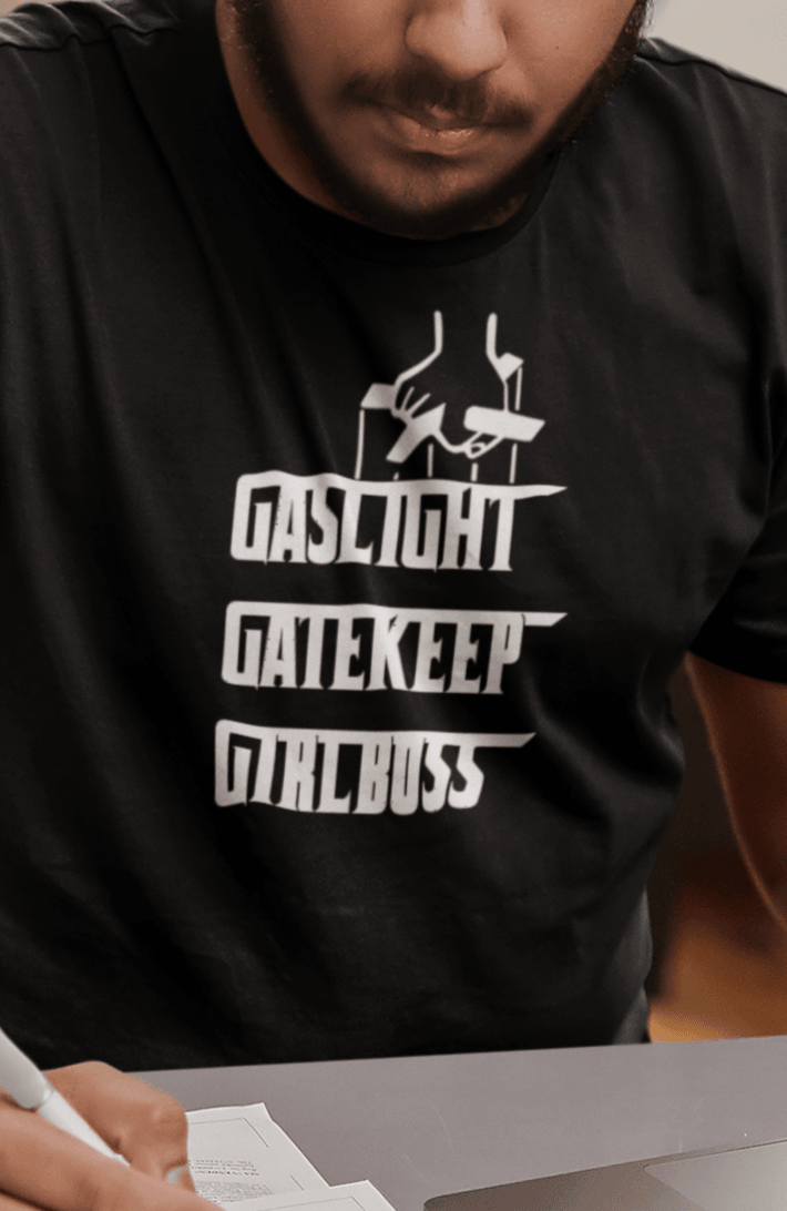 A man wears a black T-shirt that says &quot;Gaslight, Gatekeep, Girlboss&quot;.