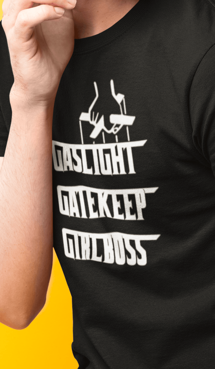 A man wears a black T-shirt that says &quot;Gaslight, Gatekeep, Girlboss&quot;.