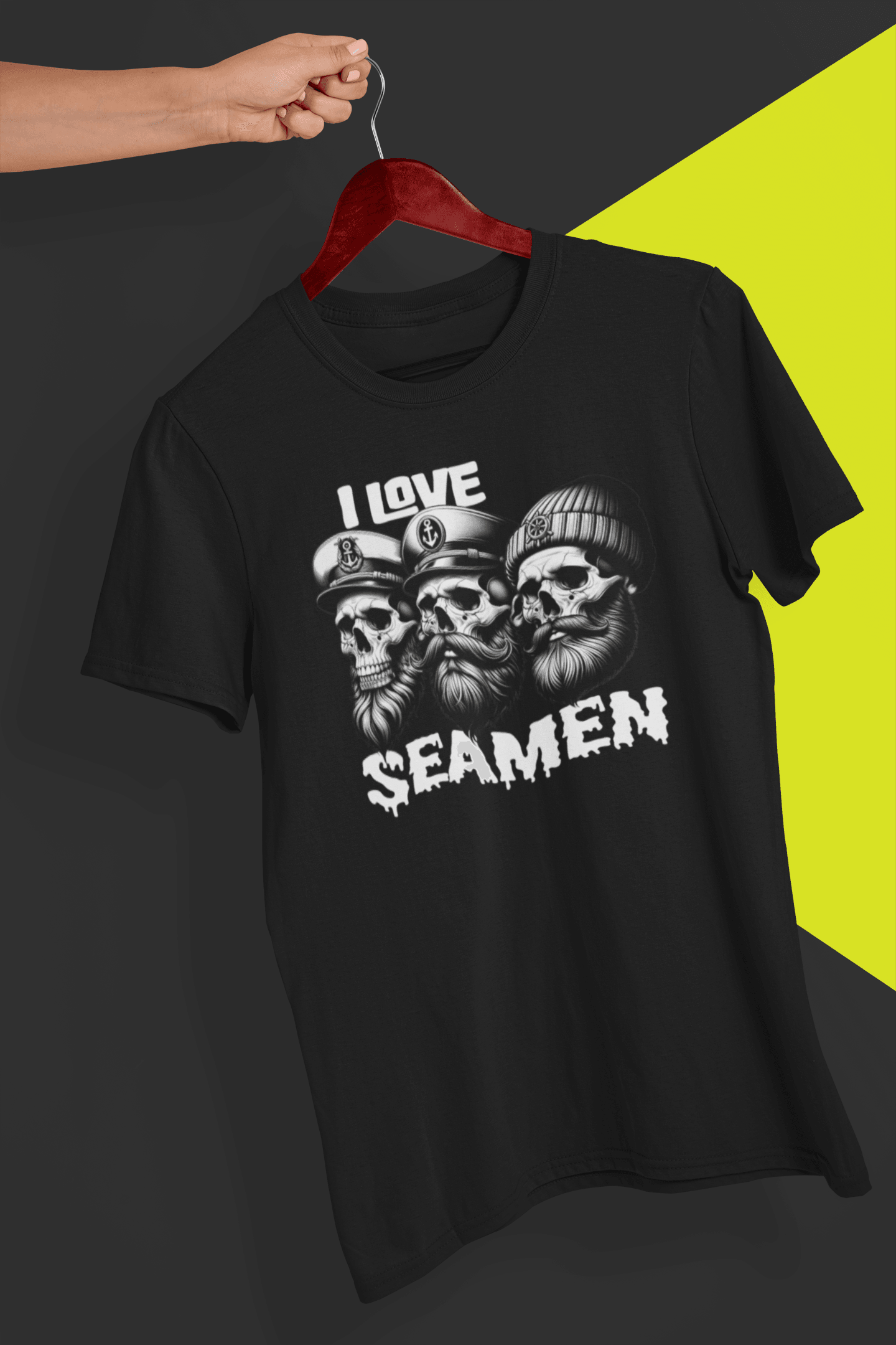 A black T-shirt with three men of the sea written &quot;I Love Seamen&quot;. is hung on a red hanger, held by a hand against a split black and yellow background.