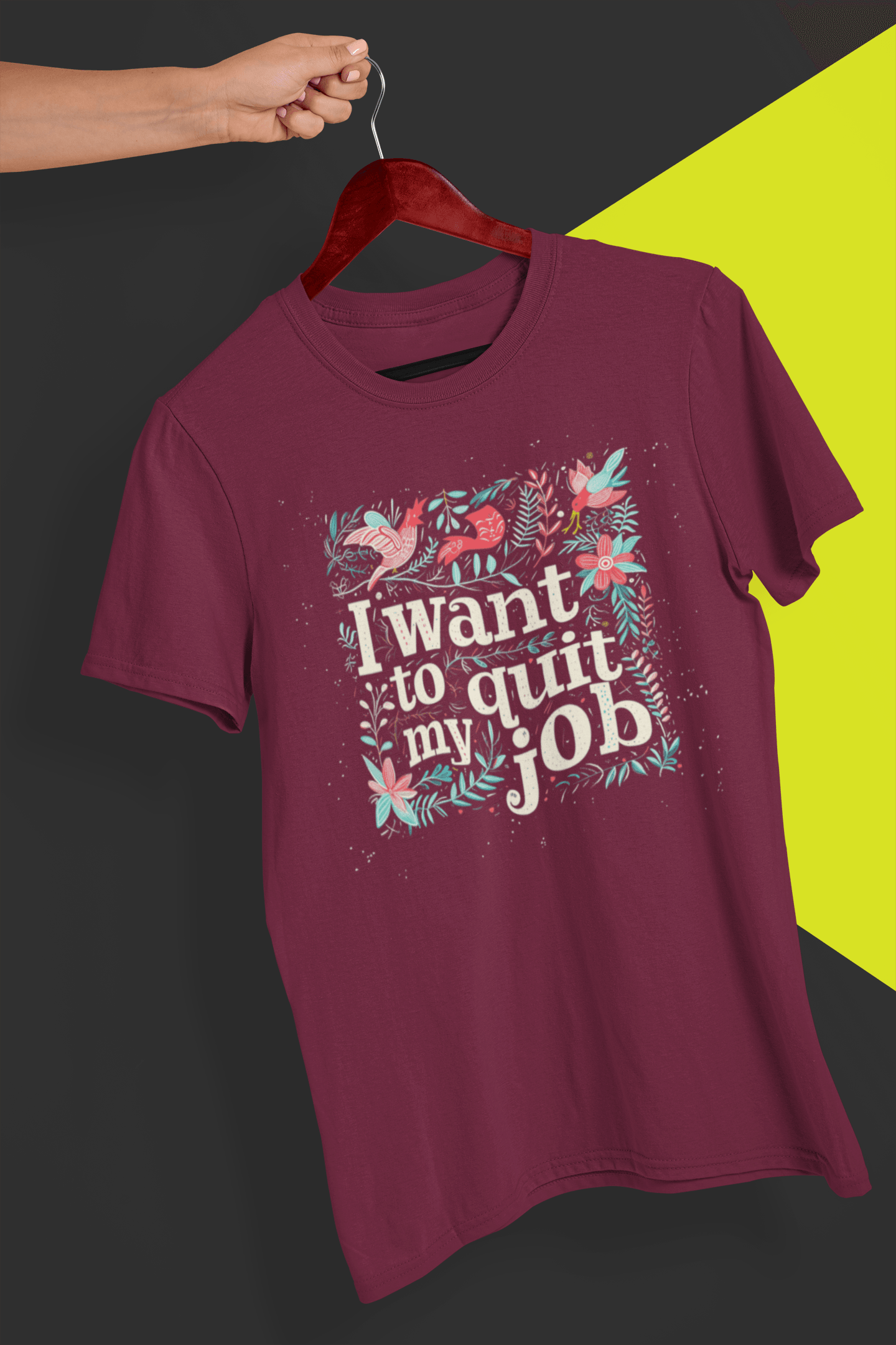 A dark red T-shirt with a typography design, saying &quot;I want to quit my job&quot;, held by a hand against a split black and yellow background.