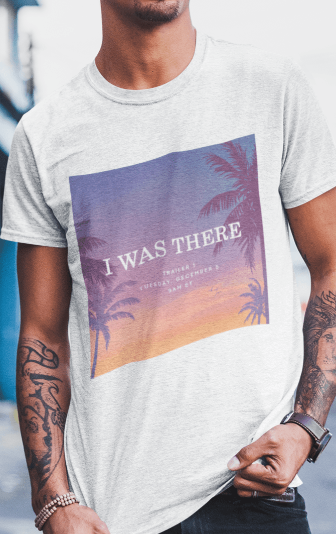 A man wearing a white T-shirt with an aesthetic miami imagery written &quot;I WAS THERE, Trailer 1, Tuesday, December 5, 9AM ET&quot;