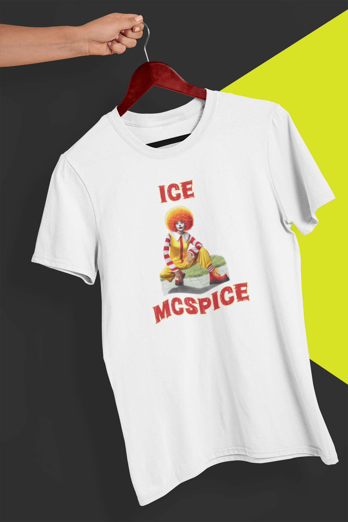 A white T-shirt featuring a woman who looks like the rapper Ice Spice dressed as Ronald McDonald, saying &quot;Ice McSpice&quot;, held by a hand against a split black and yellow background.