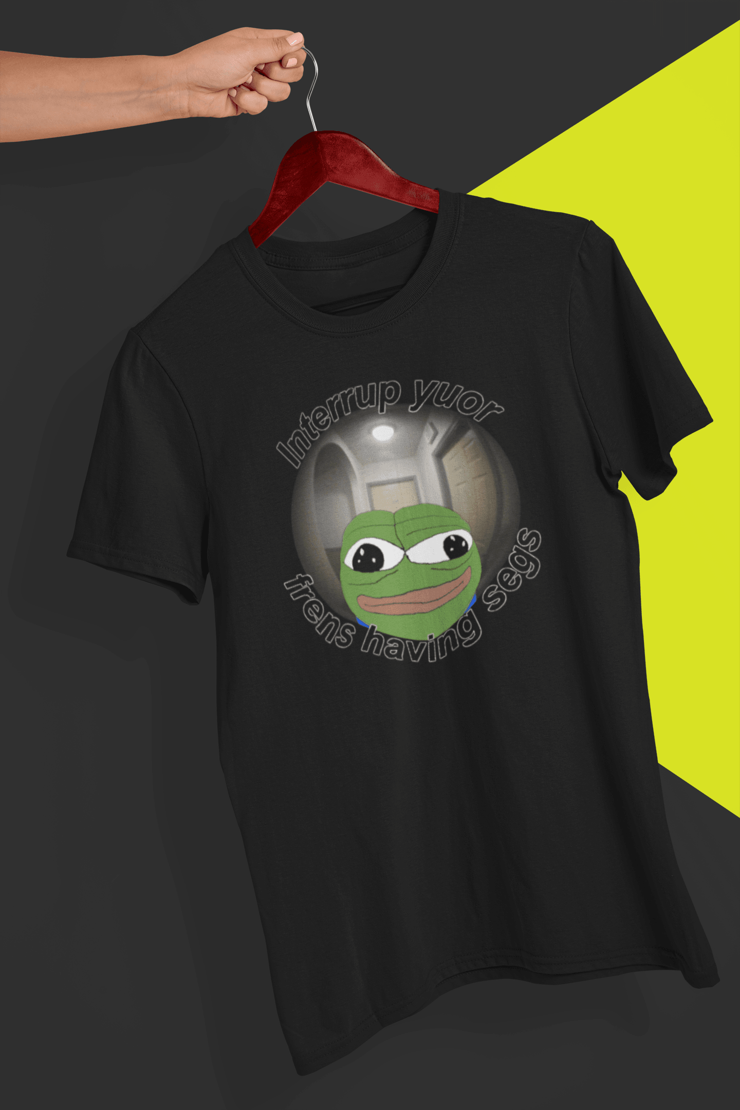 A black T-shirt featuring a peepo frog on the other side of a door peephole, saying &quot;Interrupt your friends having sex&quot; full of typos, held by a hand against a split black and yellow background.