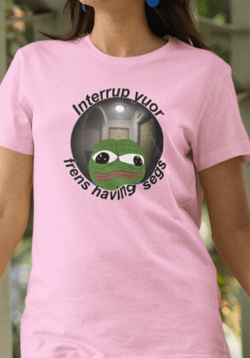 A woman wears a pink T-shirt featuring a peepo frog on the other side of a door peephole, saying &quot;Interrupt your friends having sex&quot; full of typos