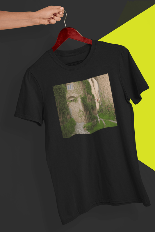 A black T-shirt featuring a landscape generated by artificial intelligence that looks like Jimmy or Saul from Better Call Saul and Breaking Bad, is hung on a red hanger, held by a hand against a split black and yellow background.