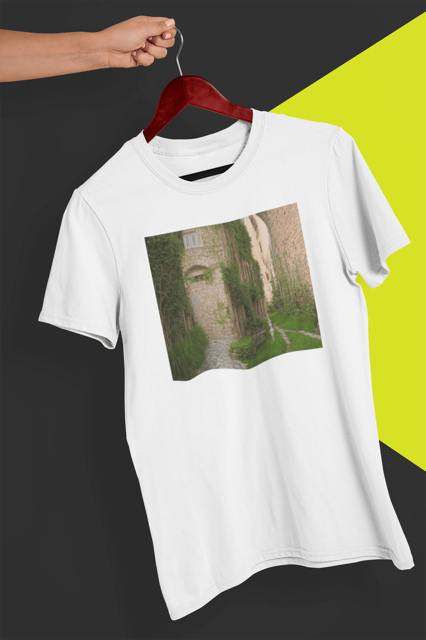 A white T-shirt featuring a landscape generated by artificial intelligence that looks like Jimmy or Saul from Better Call Saul and Breaking Bad, is hung on a red hanger, held by a hand against a split black and yellow background.