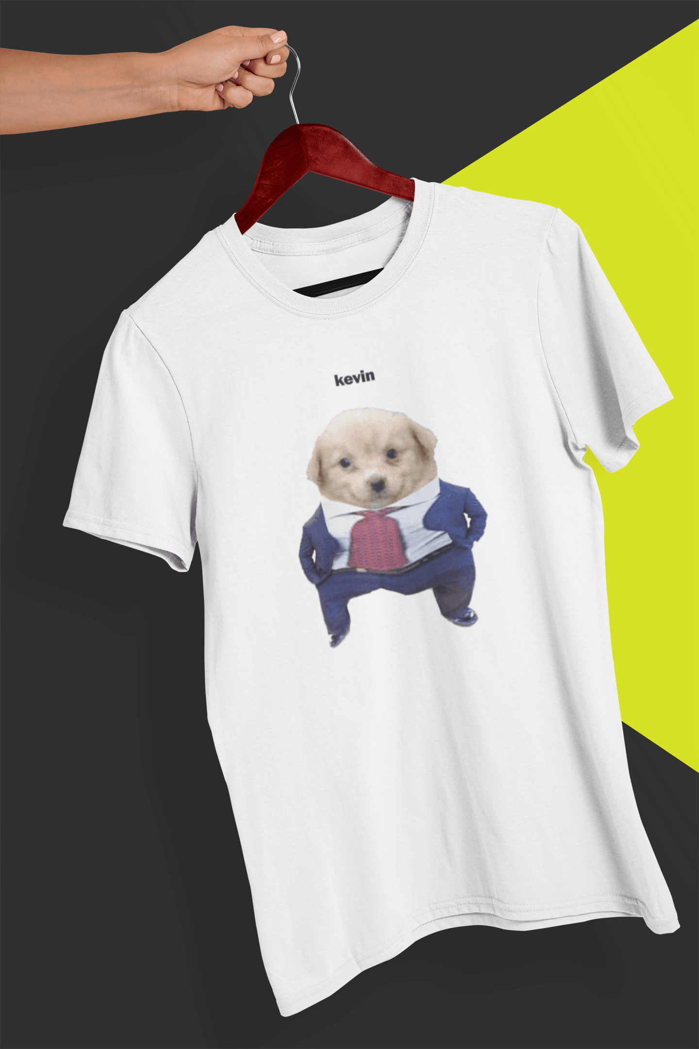 A white T-shirt with a cute dog wearing a suit written &quot;kevin&quot; on top of him, is hung on a red hanger, held by a hand against a split black and yellow background.