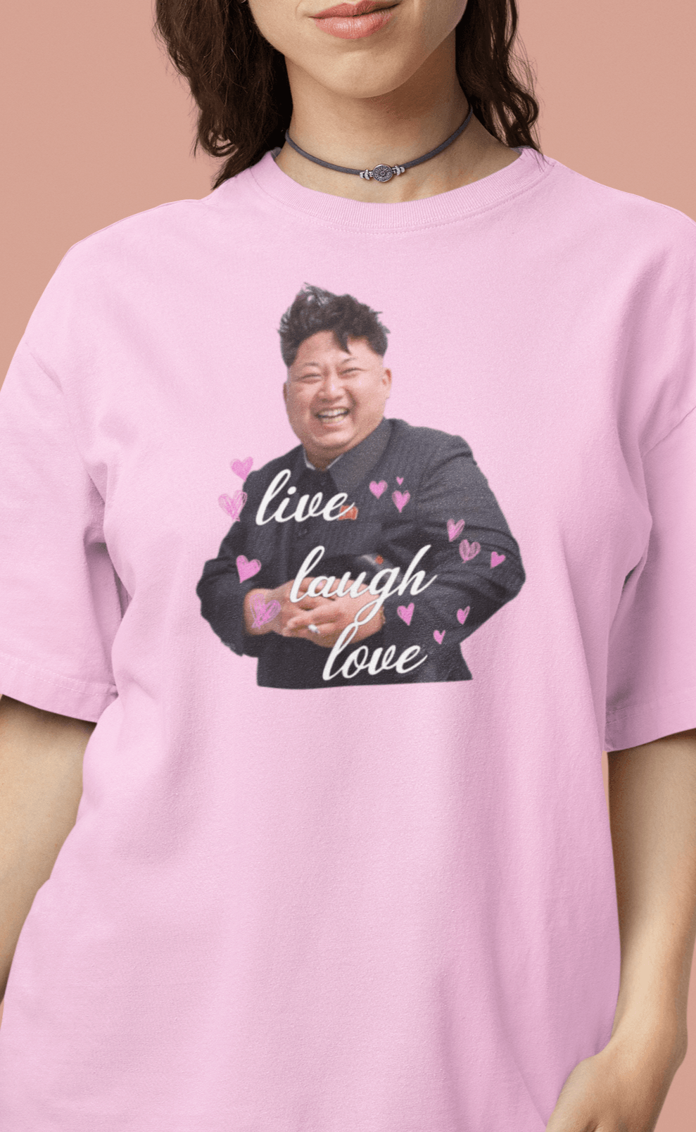 A woman wearing a pink T-shirt with kim jong un laughing saying &quot;Live Laugh Love&quot;.