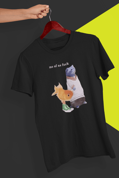 A black T-shirt with a cute cat and fish portraying Gumball and Darwin with &quot;me af as fuck&quot; written on top, is hung on a red hanger, held by a hand against a split black and yellow background.