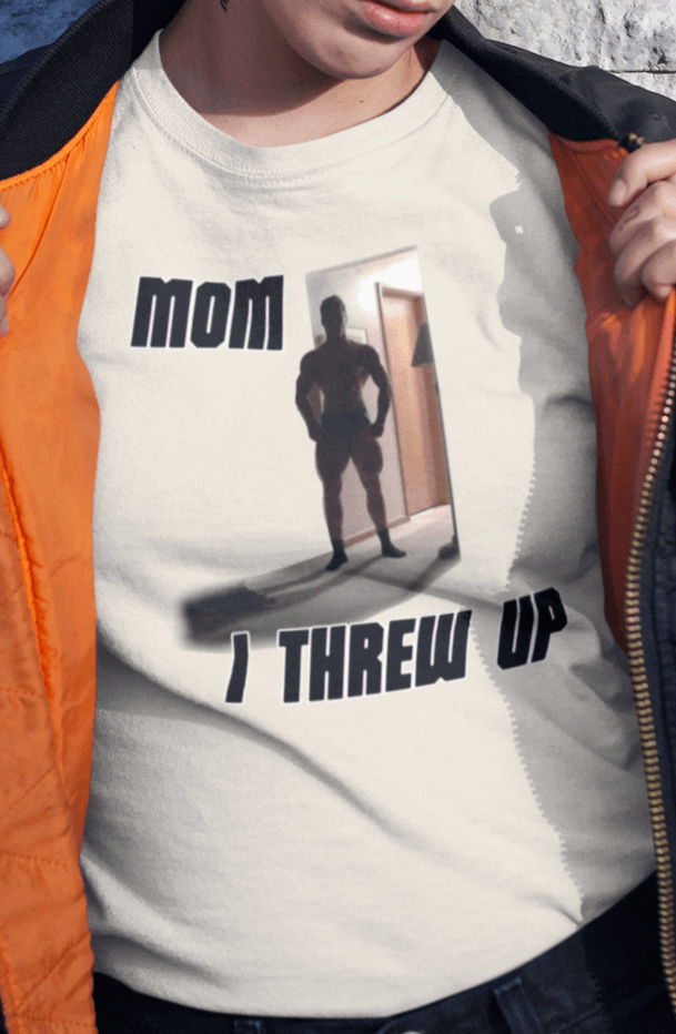 A woman wears an off-white T-shirt featuring a strong man written &quot;Mom I threw up&quot;