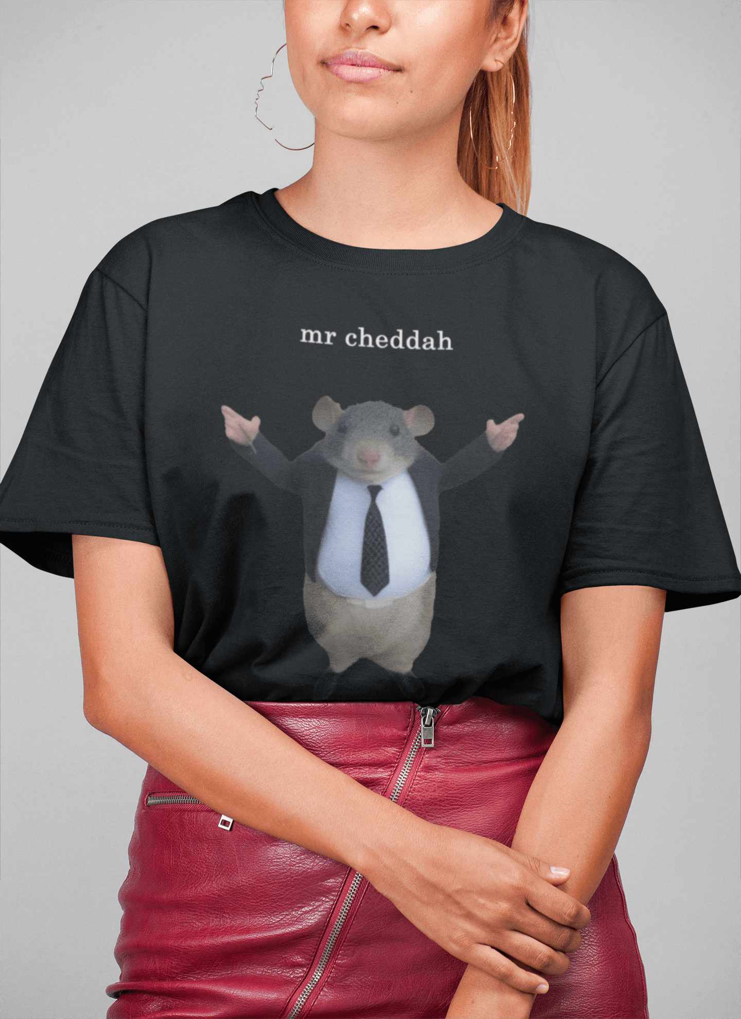 A woman wears a black T-shirt featuring a cute rat wearing a suit written &quot;mr cheddah&quot; on top of him.