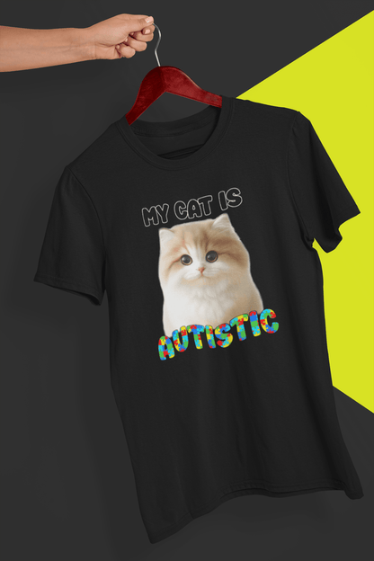 A black T-shirt with a cute cat written &quot;My Cat is Autistic&quot; on top, is hung on a red hanger, held by a hand against a split black and yellow background.