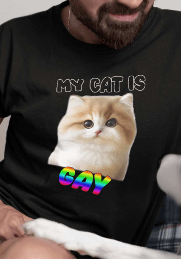 A man wears a black T-shirt featuring a cute cat written &quot;My Cat is Gay&quot; on top.