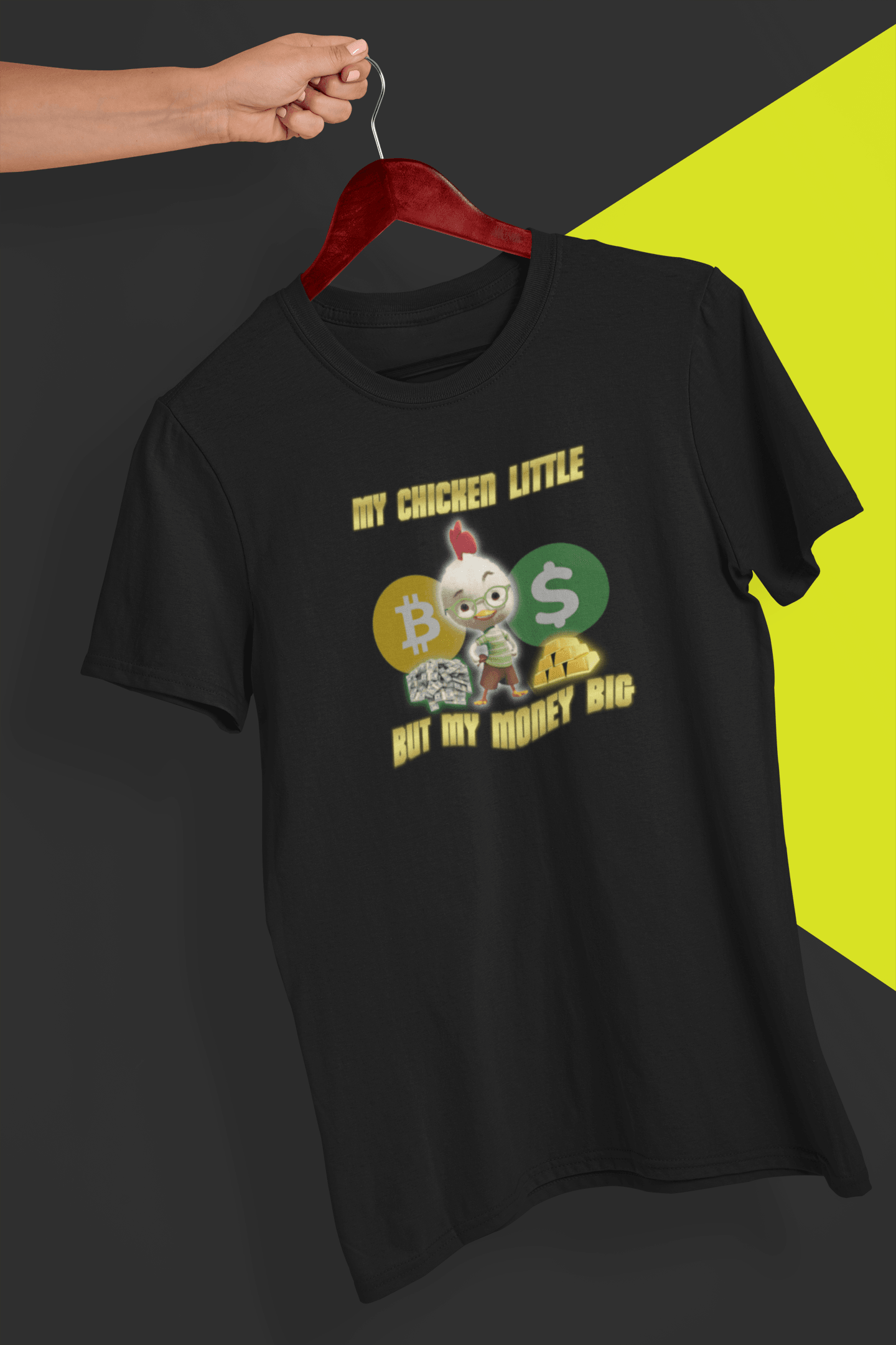 A black T-shirt featuring Chicken Little that says &quot;My Chicken Little But My Money Big&quot;, held by a hand against a split black and yellow background.