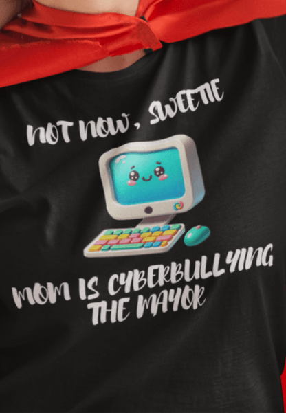 A woman wears a black T-shirt featuring a cute computer written &quot;Not now, sweetie, mom is cyberbullying the mayor&quot;.