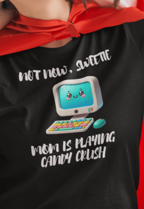 A woman wears a black T-shirt featuring a cute computer written &quot;Not now, sweetie, mom is playing candy crush&quot;.