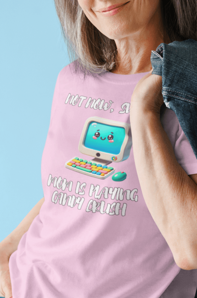 A woman wears a pink T-shirt featuring a cute computer written &quot;Not now, sweetie, mom is playing candy crush&quot;.