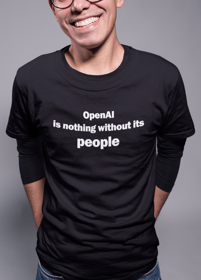 A person wears a black T-shirt written &quot;OpenAI is nothing without its people&quot;.