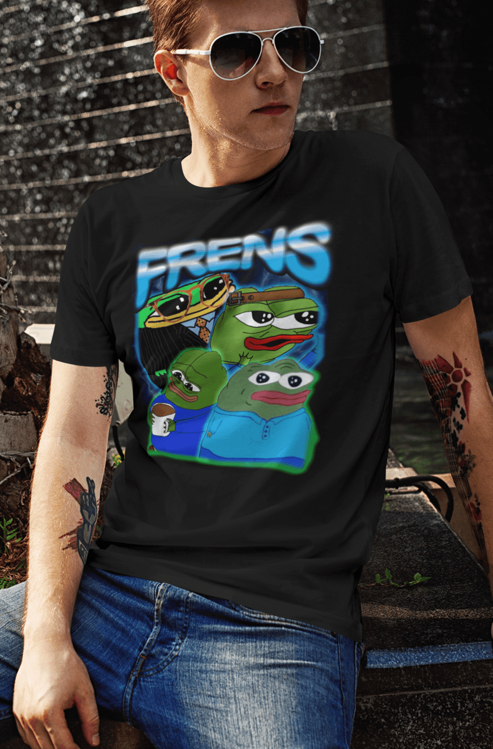 A person wears a black T-shirt featuring four cute pepes and peepos written &quot;FRENS&quot; on top.