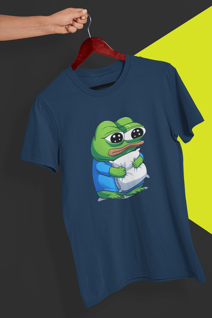 A navy blue T-shirt with a cute apu apustaja pepe in the middle hugging a pillow, held by a hand against a split black and yellow background.