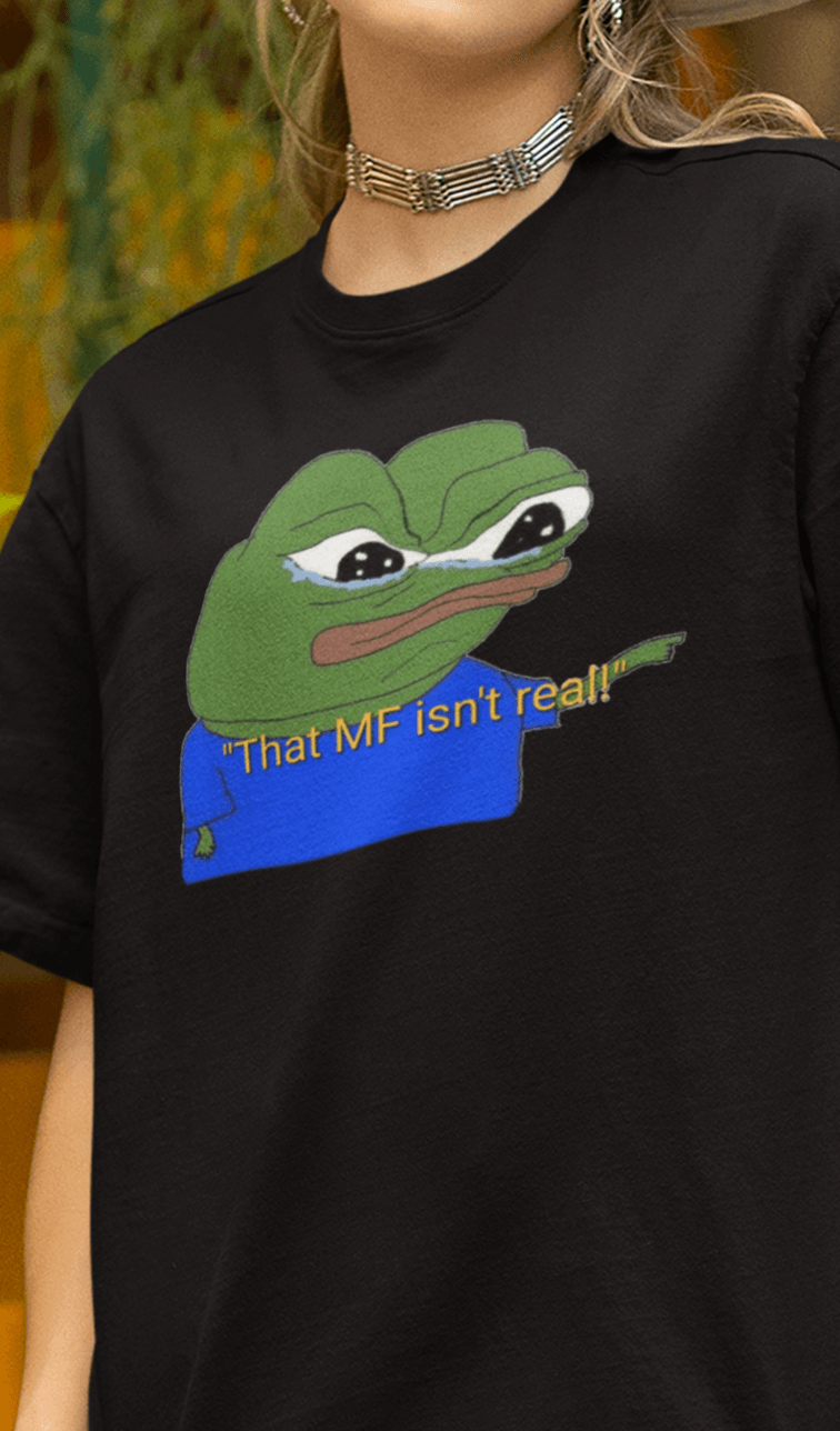 A woman wears a black T-shirt featuring a cute apu apustaja pepe in the middle pointing and written &quot;That MF isn&#39;t real!&quot;.