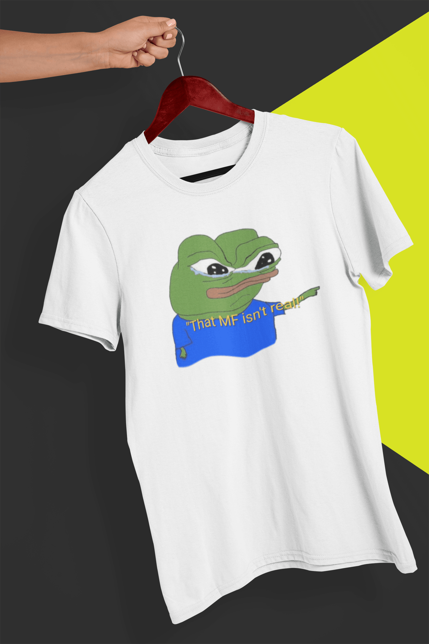 A white T-shirt with a cute apu apustaja pepe in the middle pointing and written &quot;That MF isn&#39;t real!&quot;, held by a hand against a split black and yellow background.