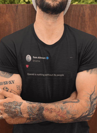 A person wears a black T-shirt featuring a tweet from Sam Altman that says &quot;OpenAI is nothing without its people&quot;.