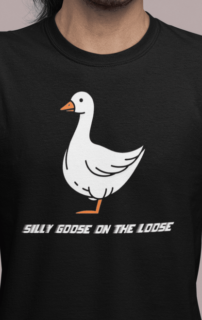 A man wears a black T-shirt featuring a cute mischievous goose in the middle, saying &quot;Silly goose on the loose&quot;.