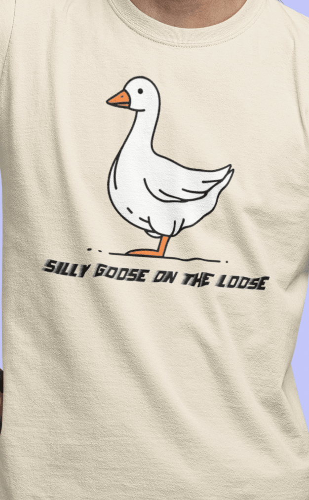 A man wears an off-white T-shirt featuring a cute mischievous goose in the middle, saying &quot;Silly goose on the loose&quot;.