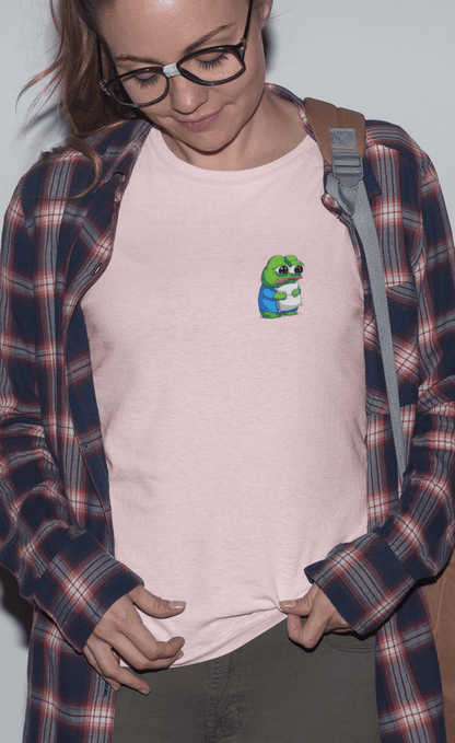 A woman wears a pink T-shirt featuring a cute apu apustaja pepe in the corner hugging a pillow.