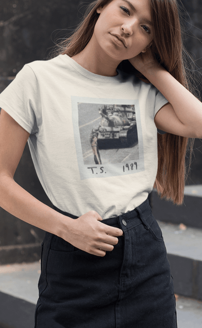 A woman wearing a off-white T-shirt with Taylor Swift in front of a tank written &quot;T.S. 1989&quot;.