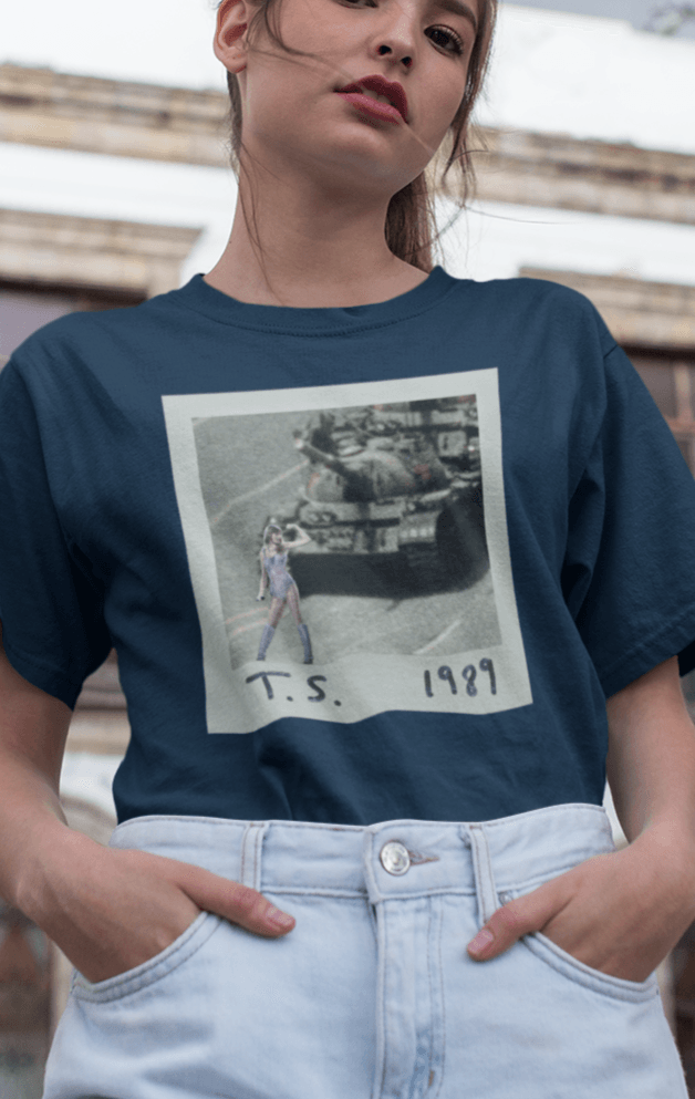 A woman wearing a navy-blue T-shirt with Taylor Swift in front of a tank written &quot;T.S. 1989&quot;.