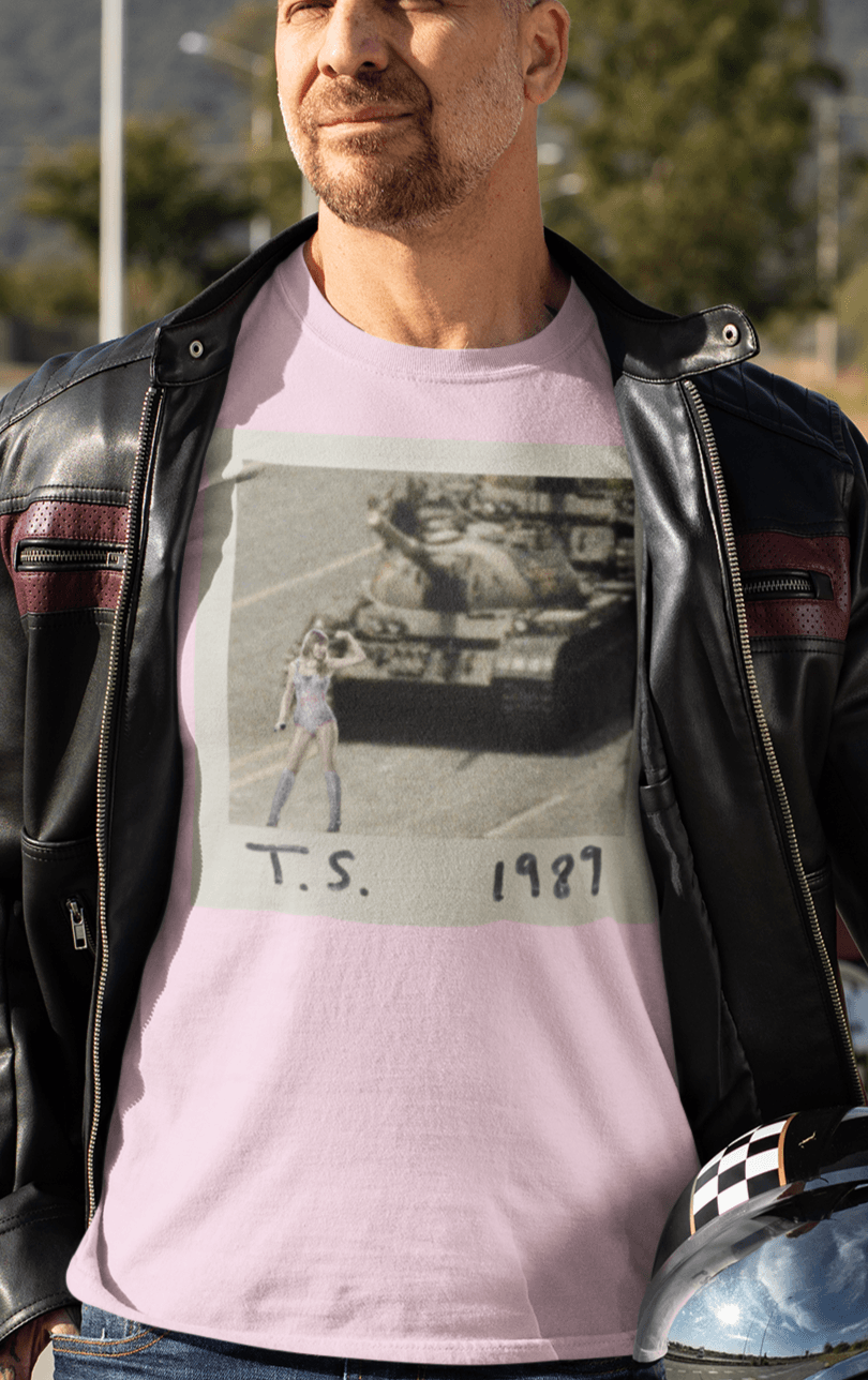 A man wearing a pink T-shirt with Taylor Swift in front of a tank written &quot;T.S. 1989&quot;.