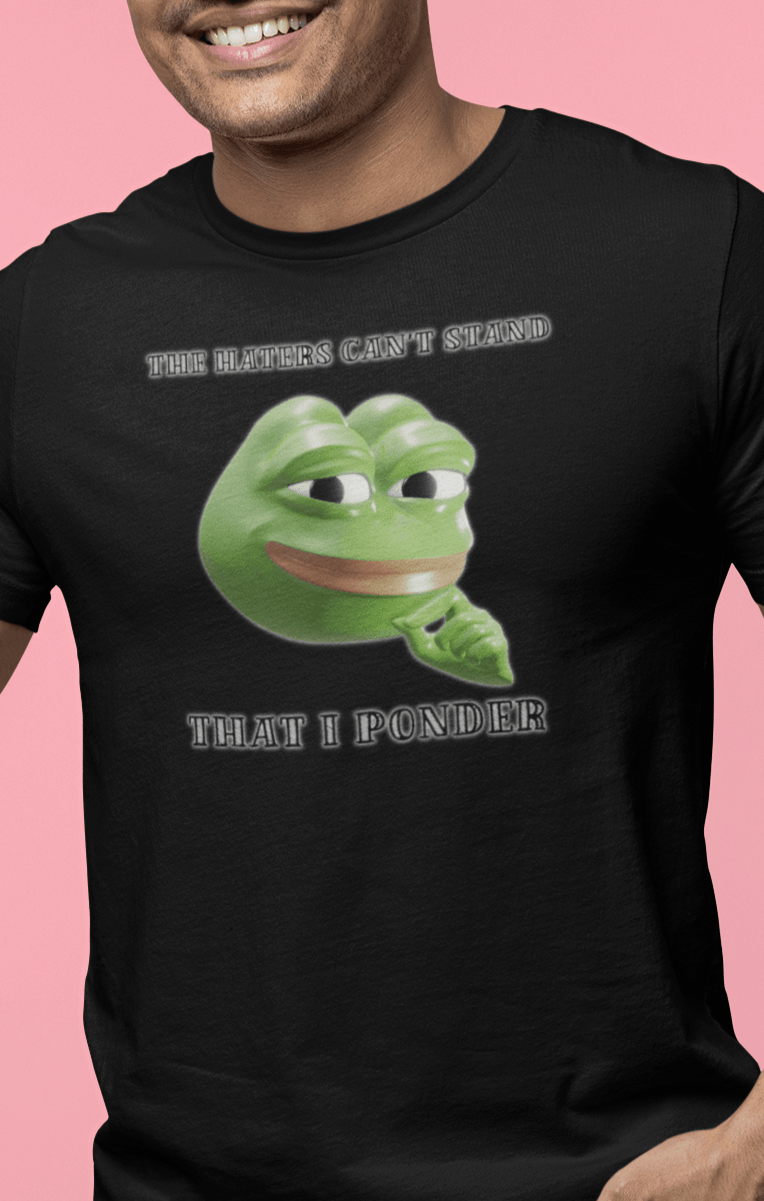 A man wears a black T-shirt featuring a funny 3d smug pepe in the middle, saying &quot;The haters cant&#39;s stand that I ponder&quot;.