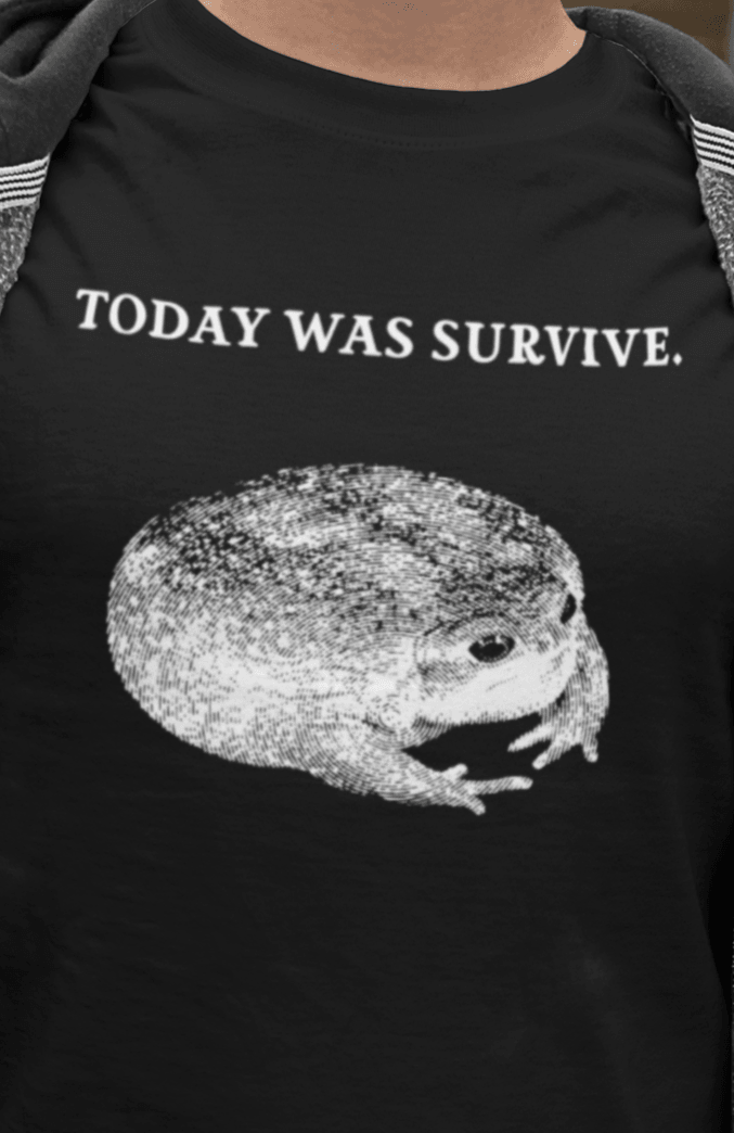 A man wears a black T-shirt featuring a cute toad, saying &quot;today was survive.&quot;