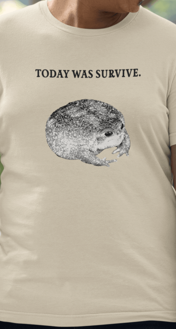 A man wears an off-white T-shirt featuring a cute toad, saying &quot;today was survive.&quot;